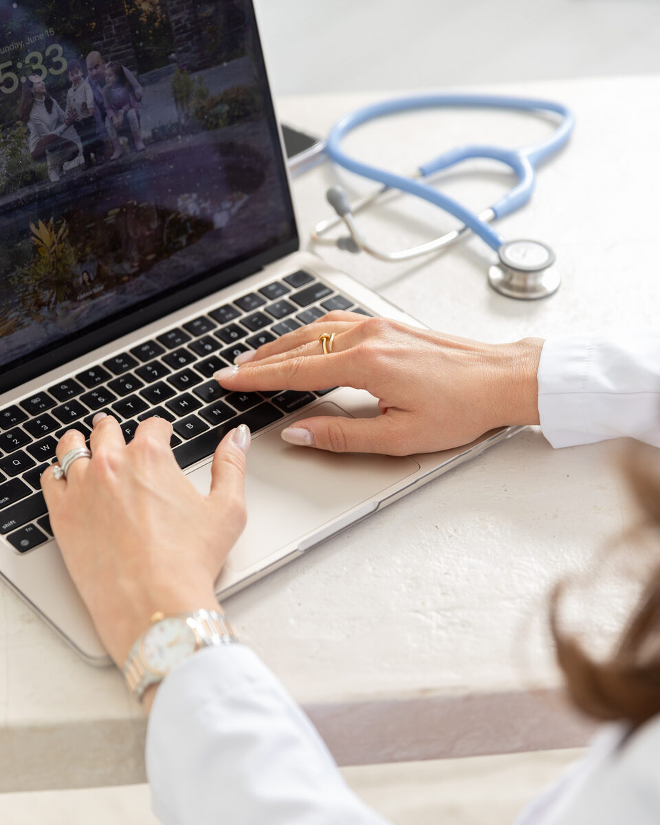 Dr. Siam working on laptop with stethoscope — virtual care
